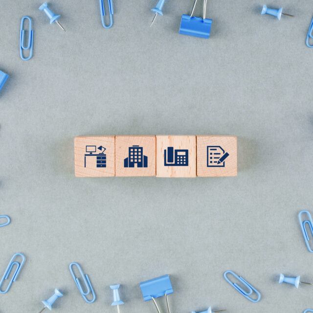 Procurement business-office-concept-with-wooden-blocks-with-icons-paperclips-binder-clips-top-view